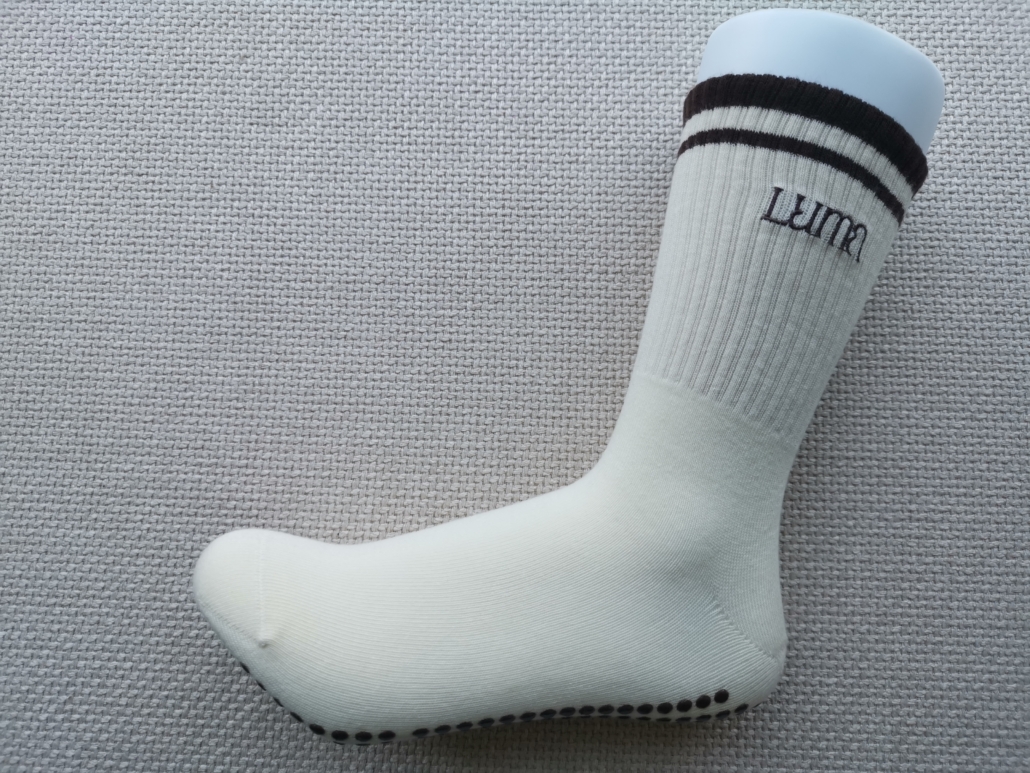 Luma grip sock on a foot model. Seamless toe and Y-stitch heel. Reinforced heel and toe. Off-white elegant sock custom made
