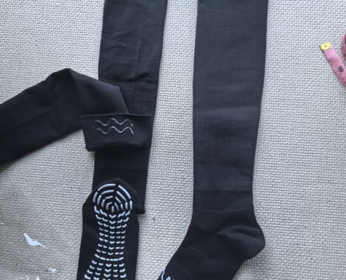 Black graduated compression knee-high sports socks with mesh upper, logo detail, and silicone grip on sole and inner cuff